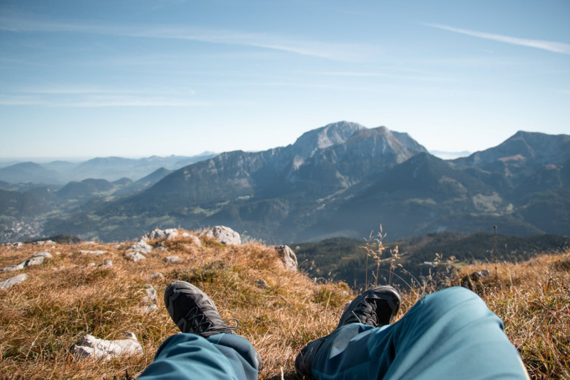 Wanderer rastet auf Gipfel mit Bergblick